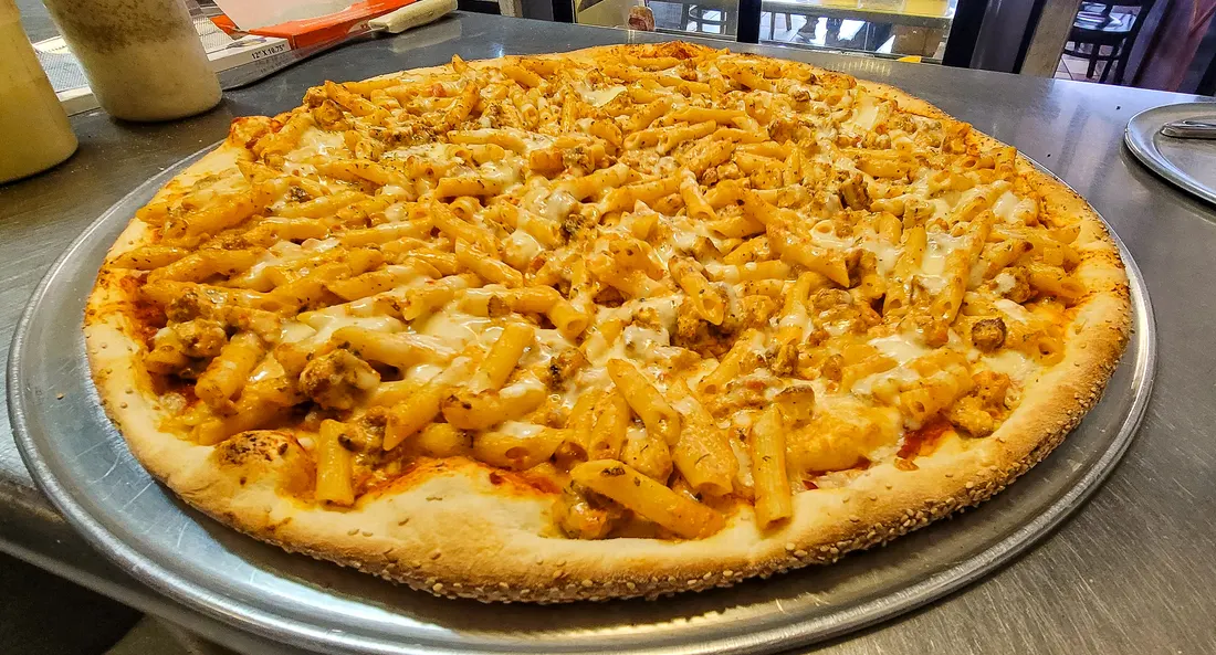 A specialty pie piled with grilled chicken and penne