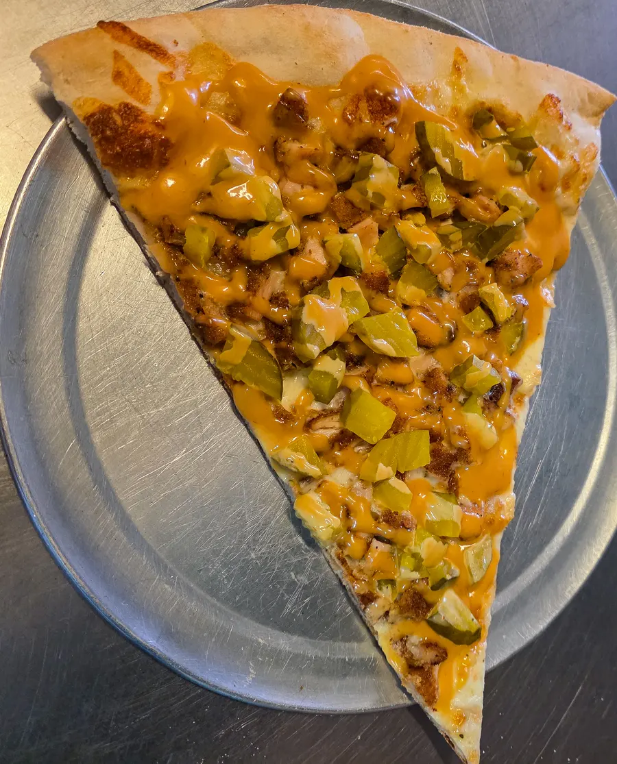 A specialty slice with chicken, pickle and cheddar